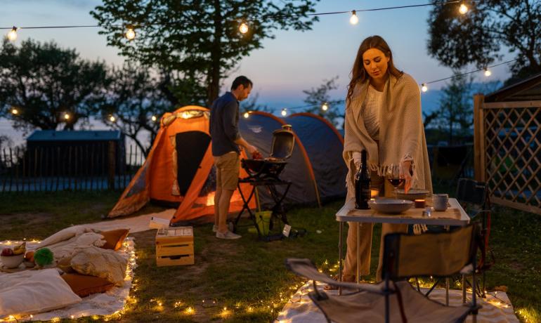 Abendcamping mit Lichtern, Zelten und Abendessen im Freien.