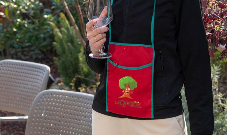 Person with wine glass and red La Quercia apron.